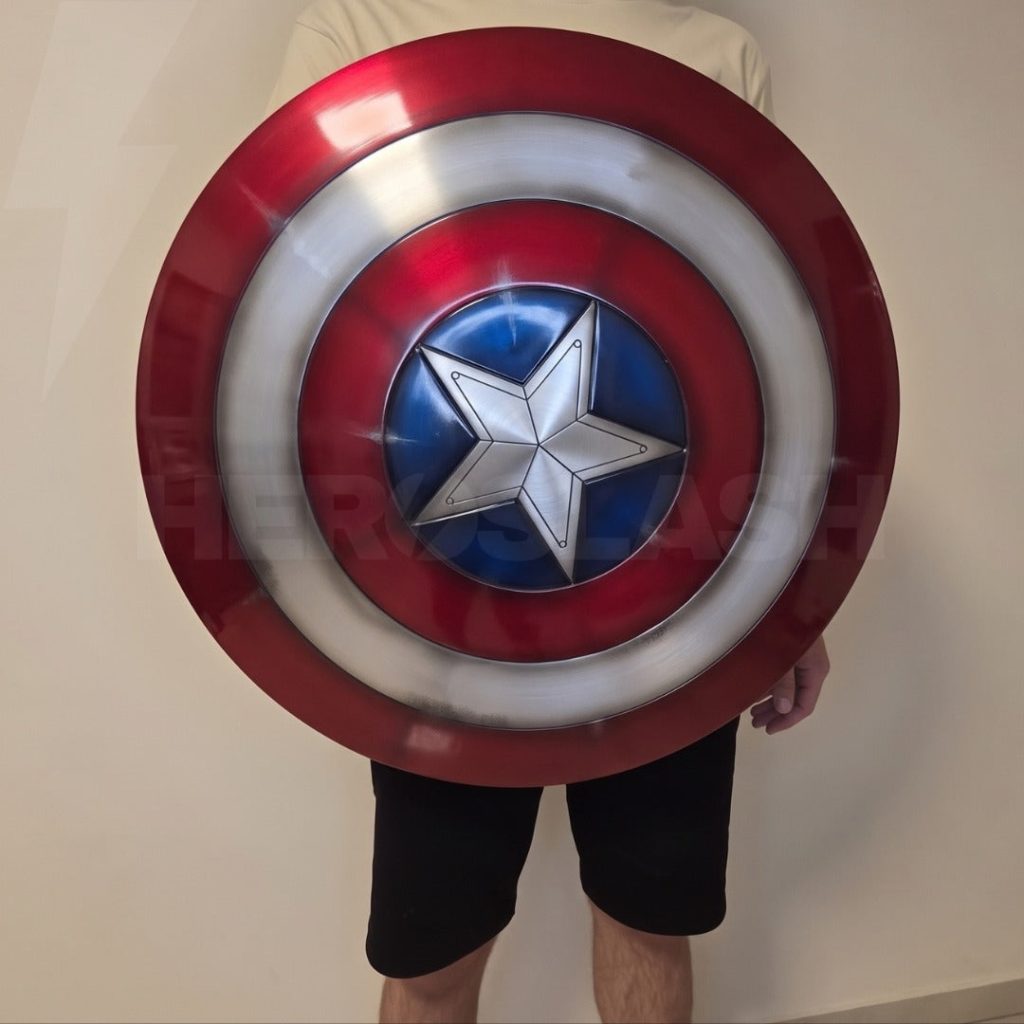 Person holding the 61 cm die-cast aluminium Captain America shield to show its full size